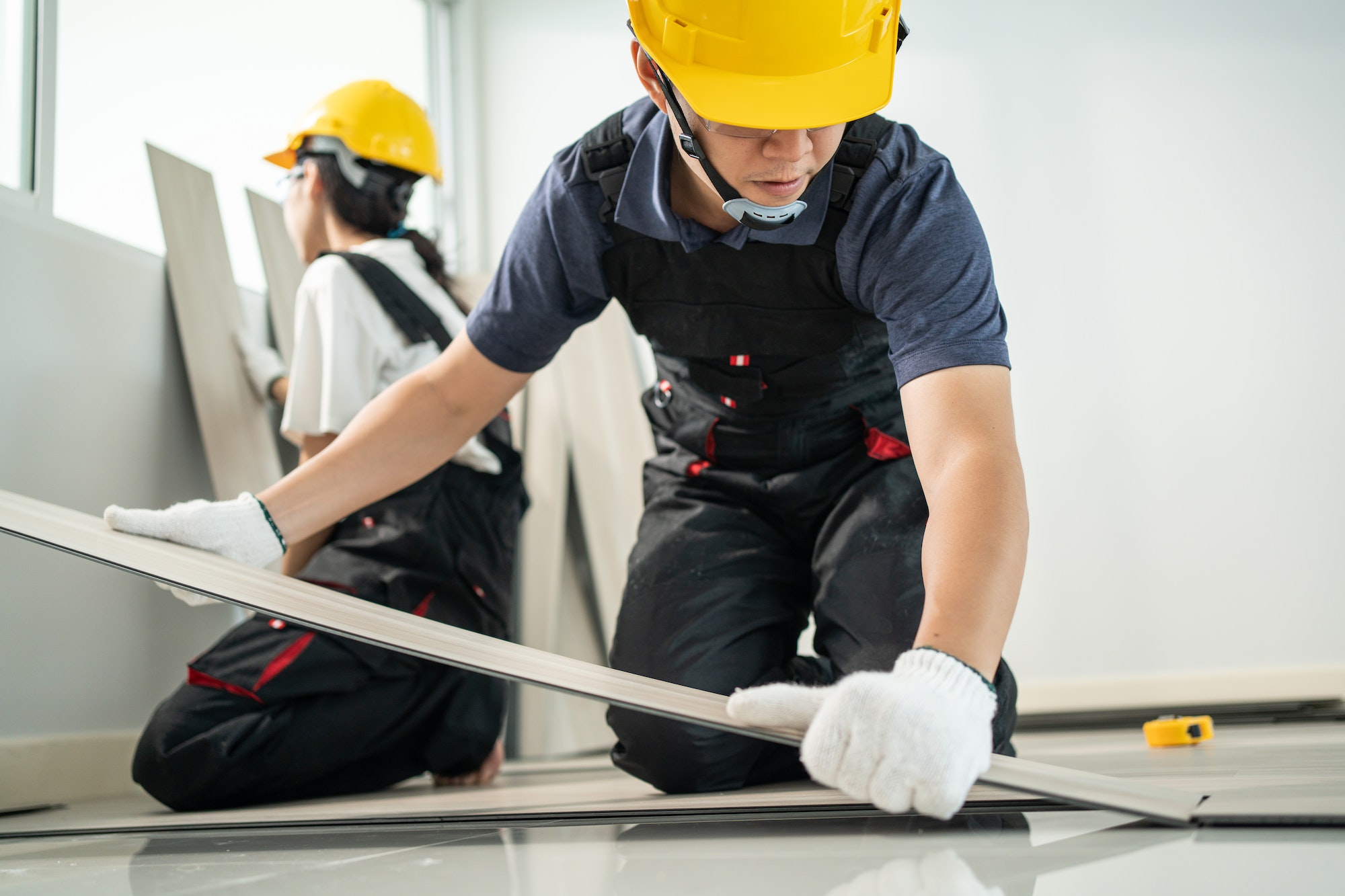 Asian Craftsman worker man and woman work by installs laminate board on floor to renovating house.