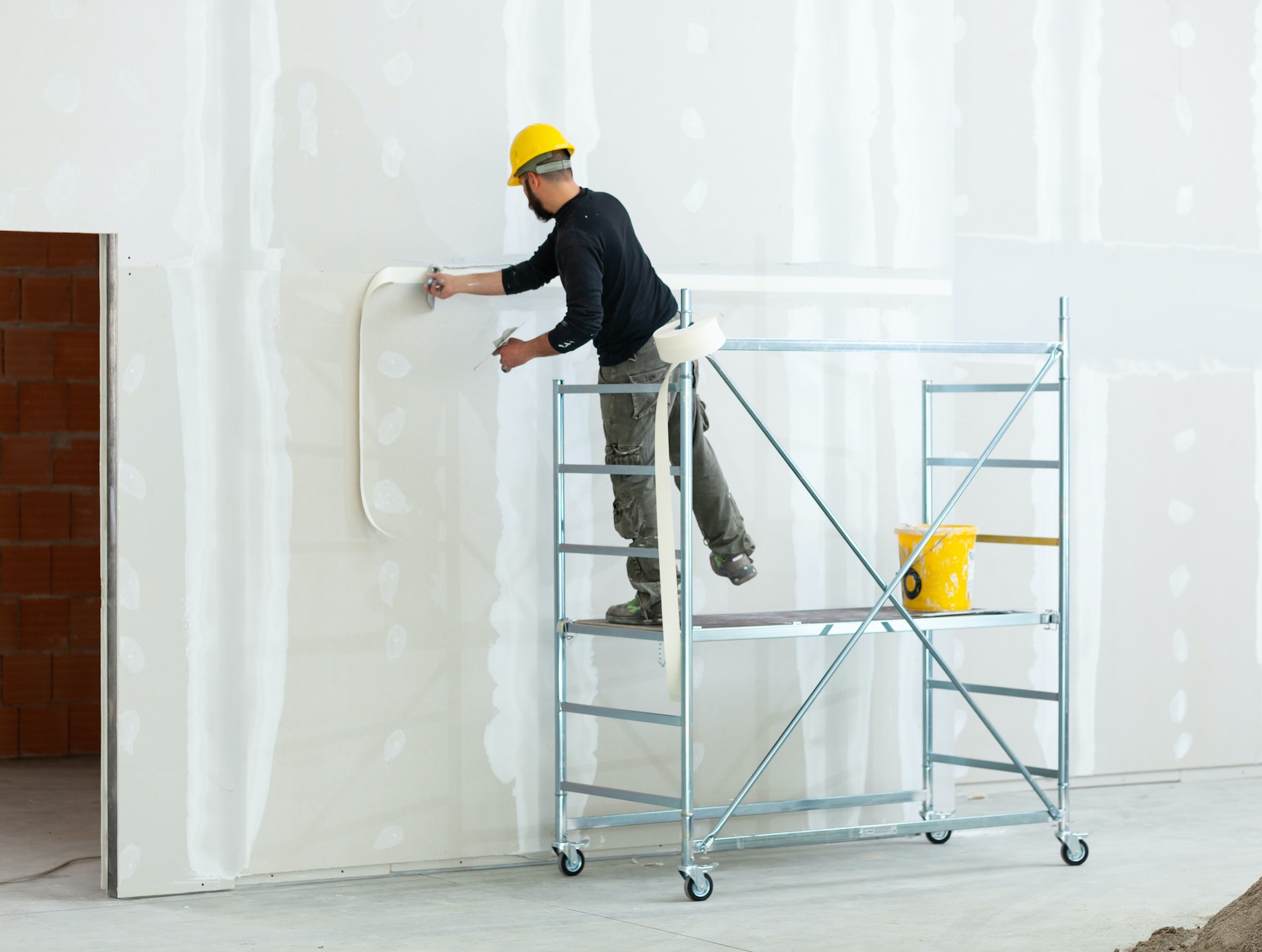 worker plastering gypsum board wall.